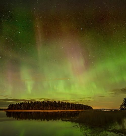 Aurora Borealis glowing vividly over a serene lake in Askainen, creating a mesmerizing natural display.